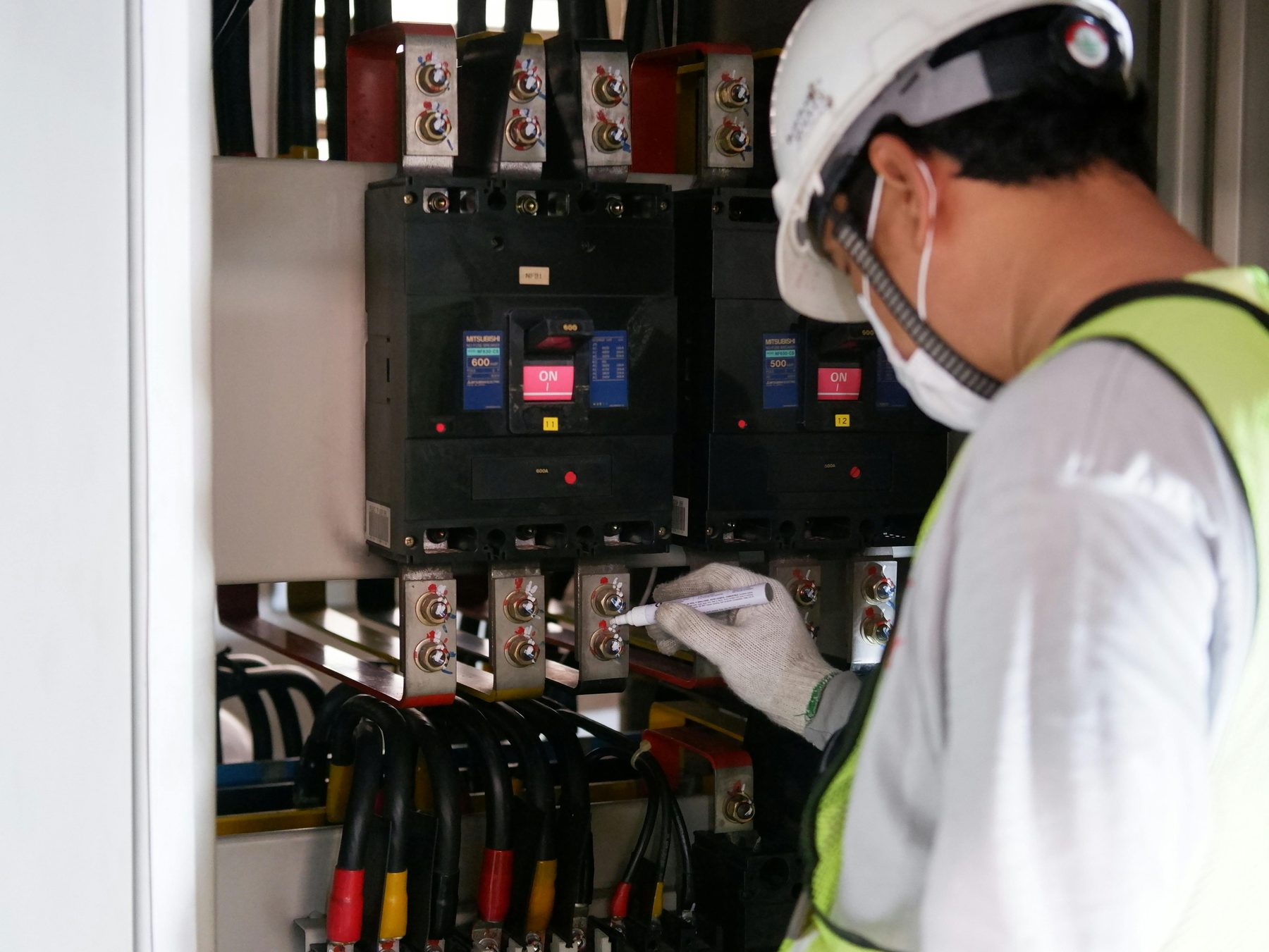 Electrical technician inspecting breaker busbar connections
