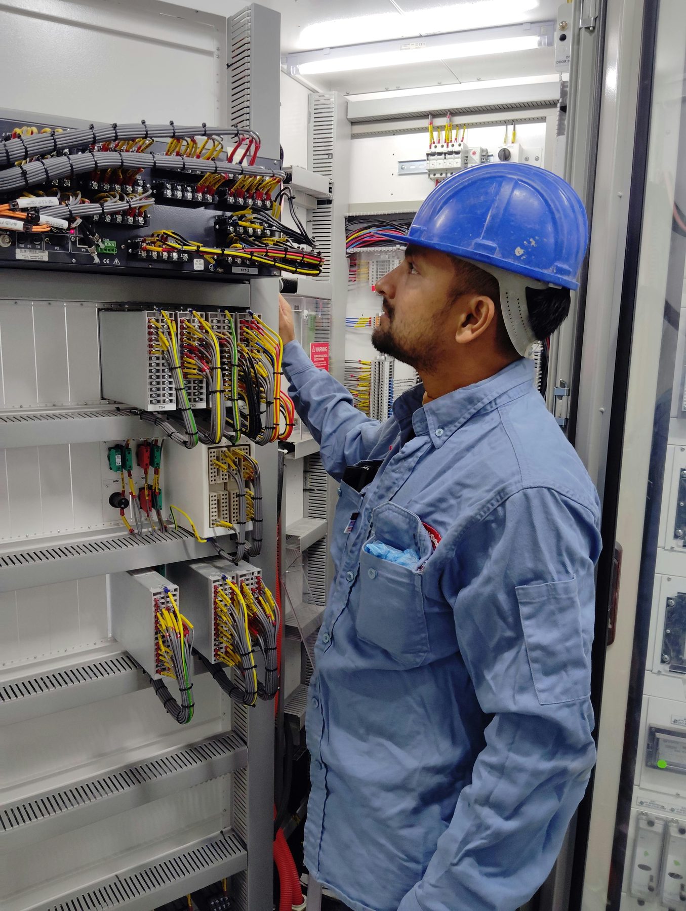 Electrical technician inspecting control panel wiring